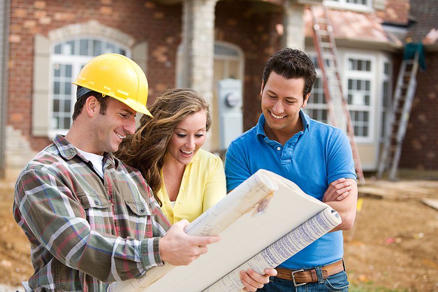Specialized Business Insurance - Construction Worker Showing New House Plans To A Smiling Couple
